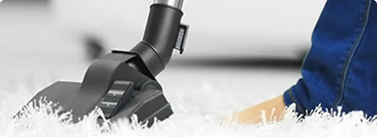 Close-up of a professional vacuuming a white carpet in Pineville.